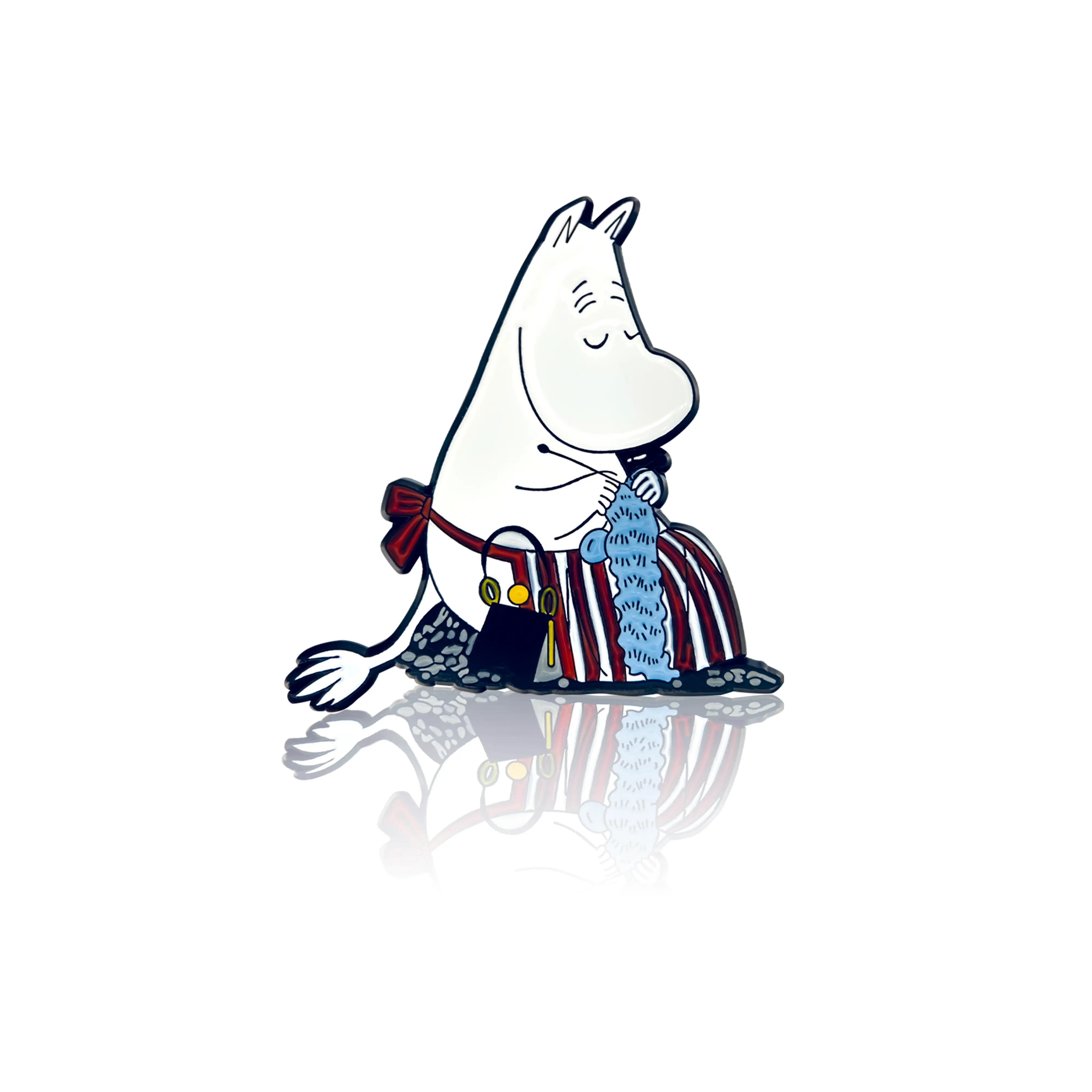 A pin badge featuring Moominmamma knitting. She is wearing a red and white apron and holding a basket and yarn.
