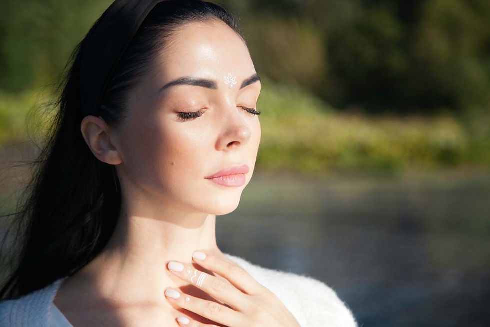 A woman with her eyes closed taking deep breaths surrounded by nature
