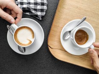Illustrating mindfulness from different cultures and traditions around the world, two hands are holding coffee cups on a table
