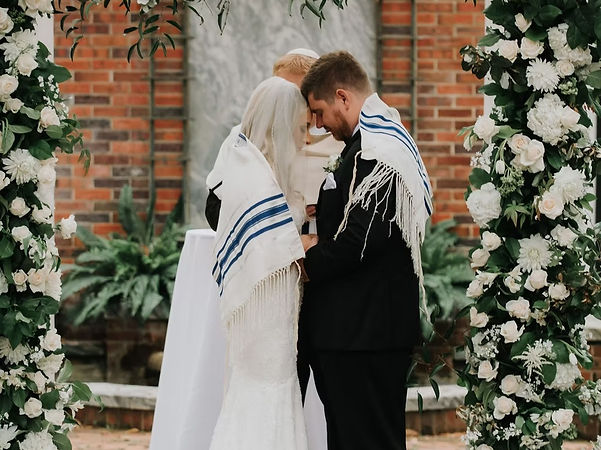 A bride and groom covered in a ceremonial wedding cloth