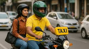 Two people wearing helmets ride a motorcycle taxi through a city street. The driver wears a green helmet and yellow shirt. Nearby cars visible.