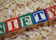 Colorful wooden blocks spelling "NIFTY" lie on wood shavings, creating a playful and creative vibe.