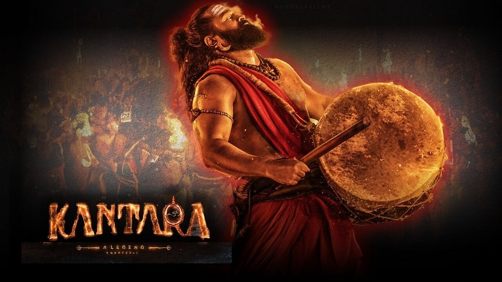 Man in red traditional attire playing a large drum with intensity. Fiery glow background, crowd in shadow. Text: Kantara. Energetic mood.