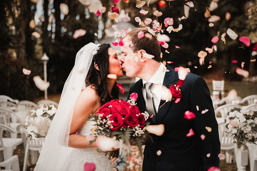 Newlywed couple sharing a passionate kiss in the elegant ambiance of Wallaceville House, surrounded by falling flower petals that add a touch of enchantment to their special moment.