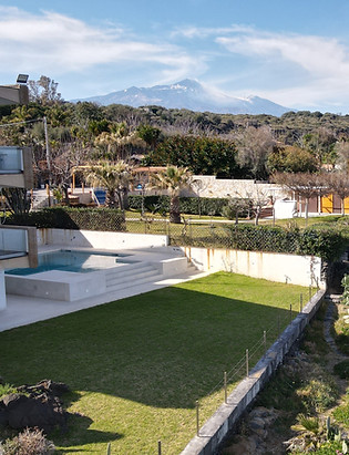 Vista aerea di una struttura con mare e montagne sullo sfondo.