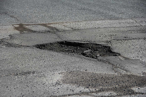 a pothole with broken asphalt in in the middle of a road.