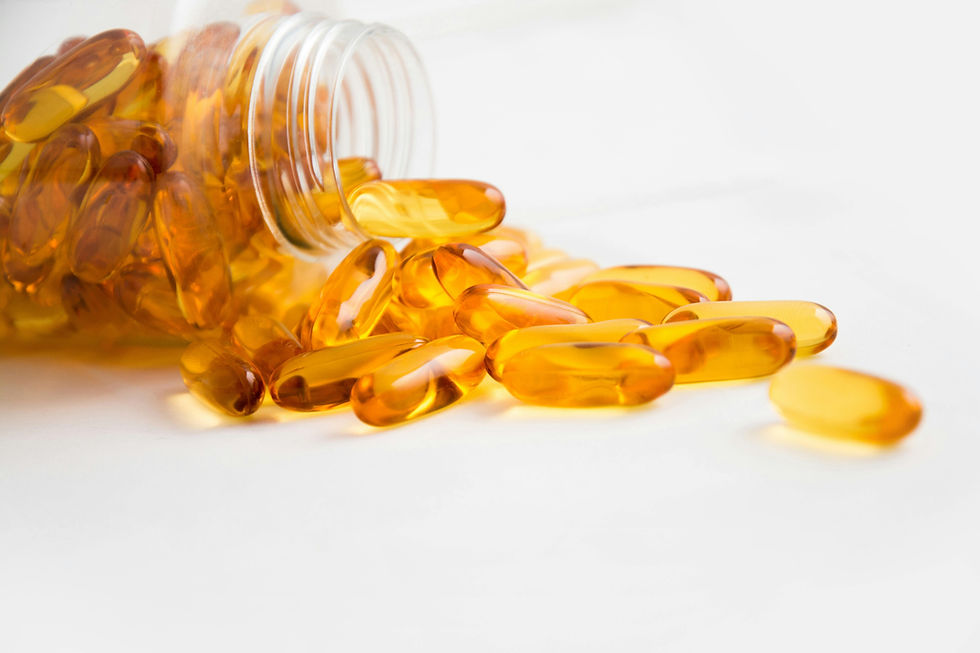Spilled amber capsules from a transparent bottle on a white surface. The scene is calm with focus on the glossy, oval pills.