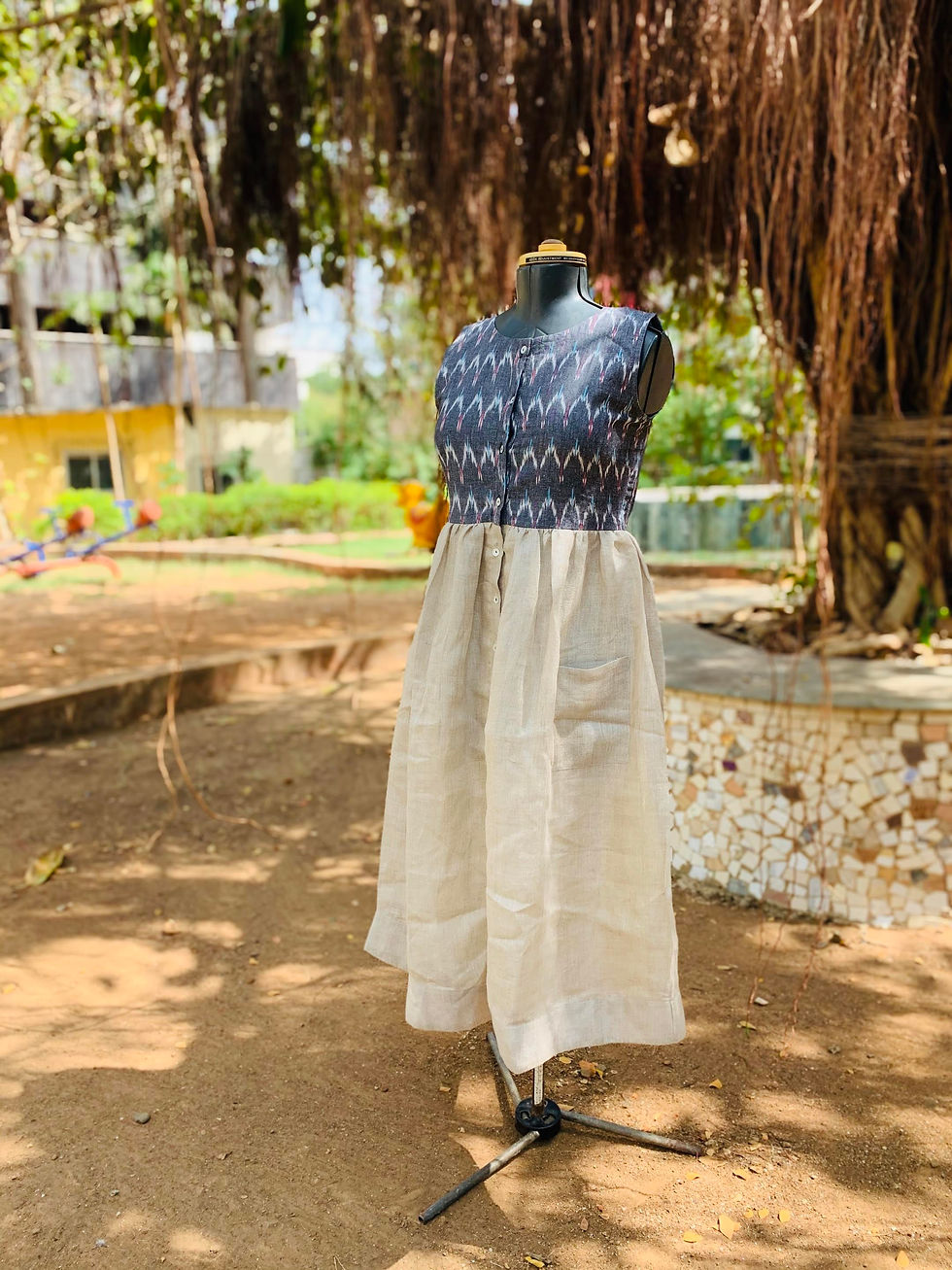 A sleeveless ikat-patterned and beige button-up dress with pockets, displayed on a mannequin under a tree with hanging roots.