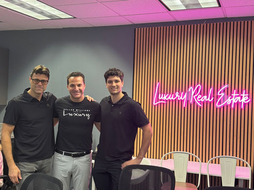 Vlad and Nick Builders attending the KW Team Meeting with local realtors, standing together in front of a Luxury Real Estate neon sign while discussing contractor and realtor partnerships in Los Angeles.