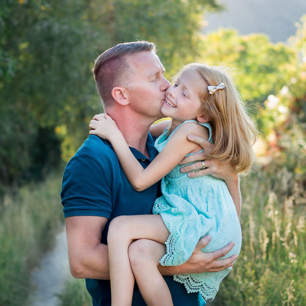 Daddy snuggles little girl in fall sunset lighting