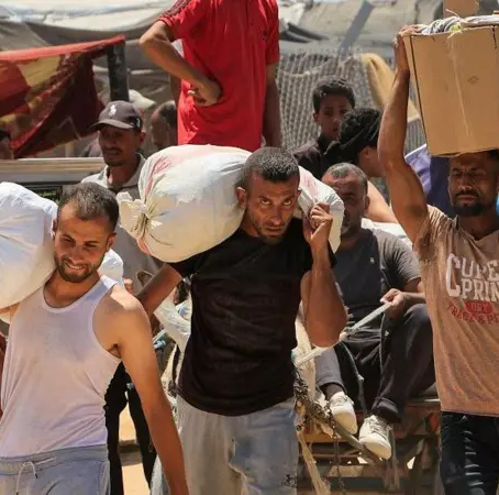 Palestinos llevan suministros que recibieron de la Fundación Humanitaria de Gaza, en Jan Yunis.