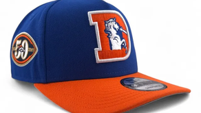 Gorra azul y naranja con logo de caballo en letra "D". Incluye parche conmemorativo "50" y "2009". Diseño deportivo y colorido.