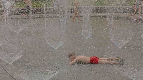 ▲ Un niño se refresca en una de las pocas fuentes que funcionan en Kiev, capital de Ucrania, donde el termómetro alcanzó 32 grados, lo que es insólito para este país.Foto Afp