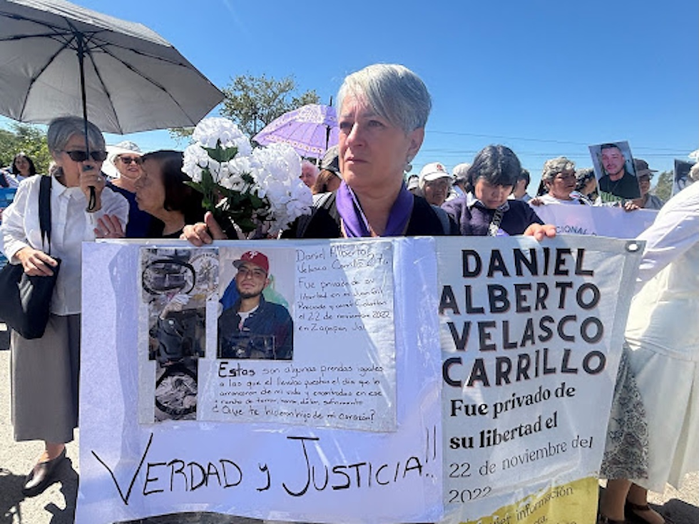 Carmen Carrillo llevó a Teuchitlán una pancarta con el nombre de su hijo desaparecido e imágenes de las prendas y objetos que le hacen pensar que sus restos están en el rancho Izaguirre. (Marcela Turati)