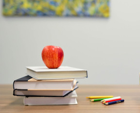 Stack of books, apple on top, colored pencils photo courtesy of Stencil