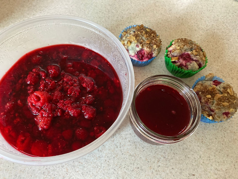 Bowl of raspberries in mint syrup, three raspberry muffins, and one jar of raspberry sauce