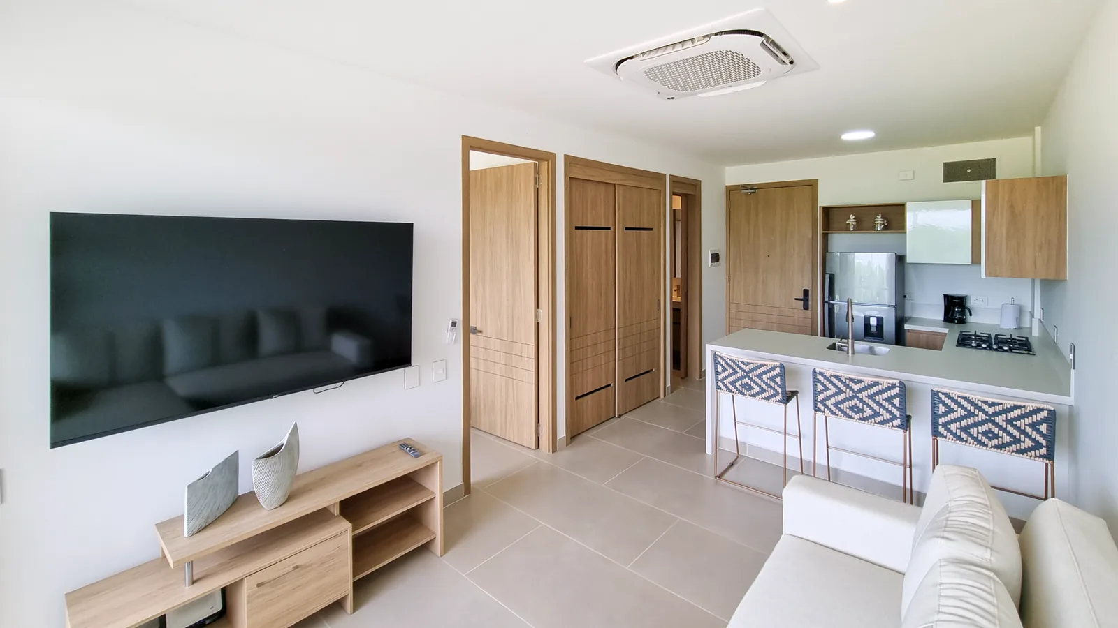 Sala con televisor y cocina al fondo del apartamento K12N en Baia Kristal.