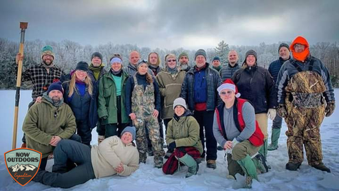Group of winter campers on a frozen lake posing for a picture during the frozen butt hang