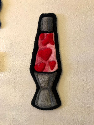 Lava lamp shaped tufted rug. The inside of the lava lamp is pink and the "lava" is in the shape of red hearts.