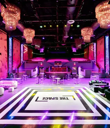 The Space at Westbury showcases a chic club setting with white couches and striking black lighting accents.