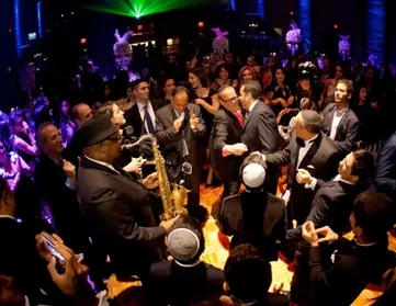 Live music entertainment at Bar Mitzvah. Saxophone player in the middle of dane floor with people dancing around.