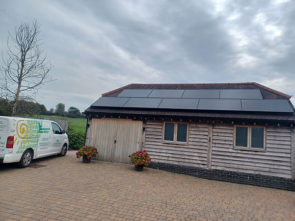 A wood clad building with solar PV on the roof and a company van parked beside it.