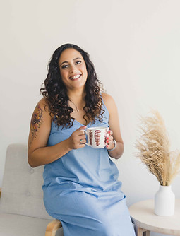 woman in blue dress holding a mug, smiling