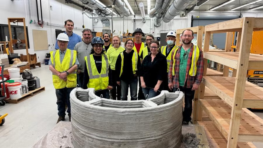 UW-Stout Polytechnic faculty, staff and others pose with a concrete planter, one of the first items printed with the university's new 3D concrete printer.