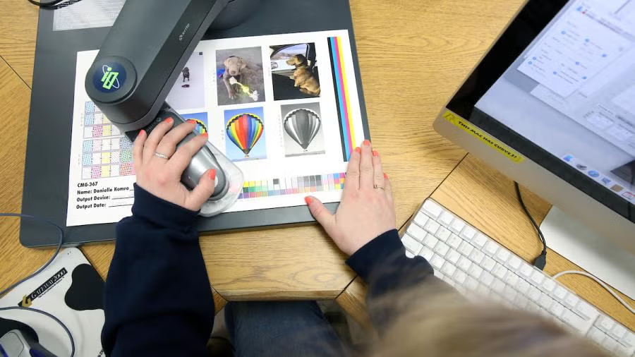 Graphic communications students check print design quality in a lab on campus.