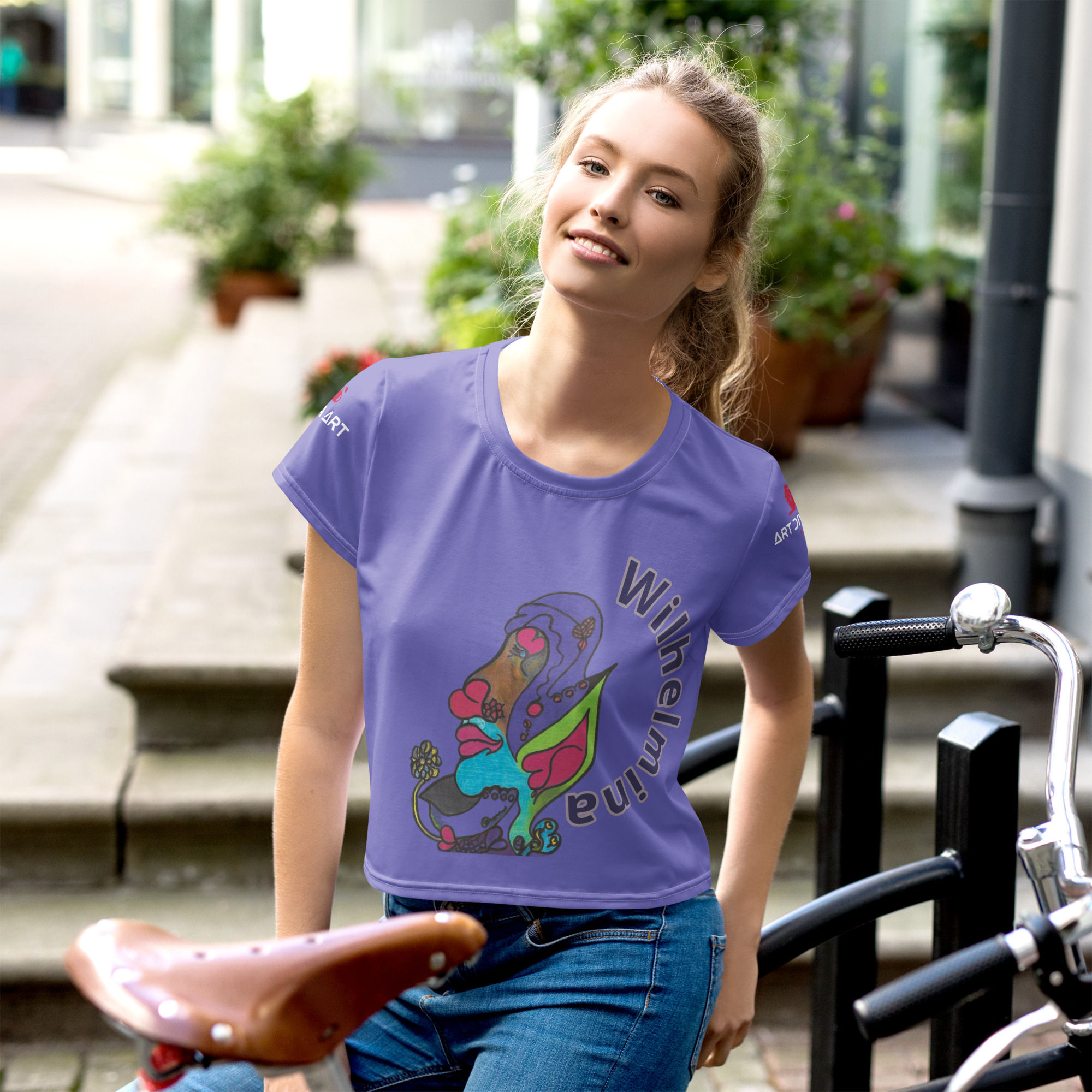 Woman wearing purple t-shirt with art, smiling outdoors by a bicycle. ArtDivaArt
