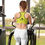 Thumbnail: Woman using elliptical machine, wearing a sports bra with text, Peeking Twin - Sports bra, indoors.