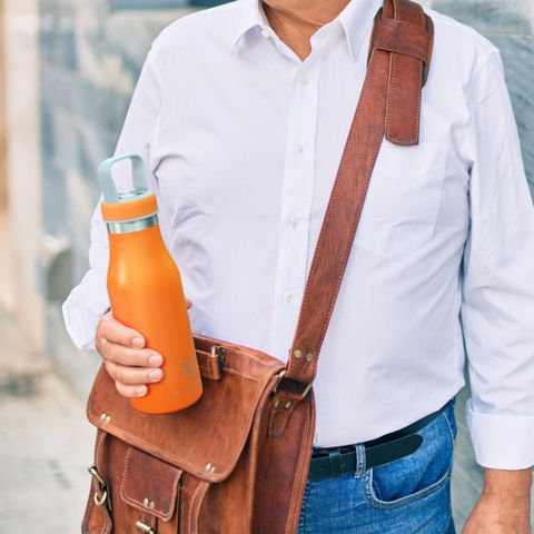 Senior man wearing satchel bag and holding VitaBottle in one hand