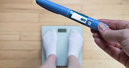 Woman on weighing scales showing ozempic injection pen