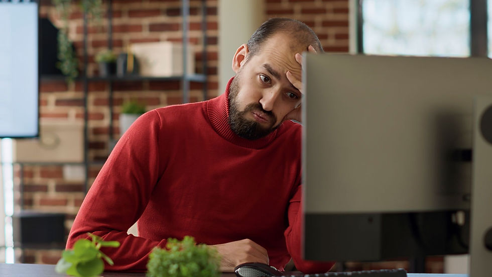 Man in front of computer looking exasperated.