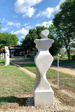 Abstract monumental limestone sculpture of a woman's figure, in a sculpture garden