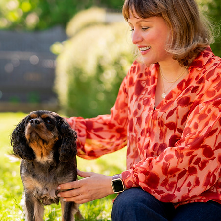 Danielle Slater sitting in a garden with her dog, offering a warm welcome to new therapy clients.