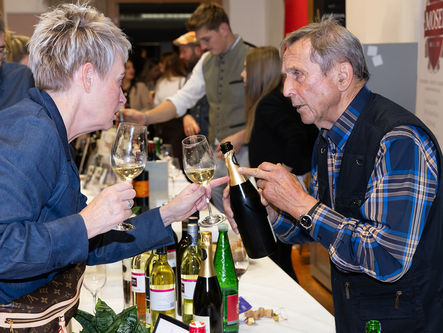 Besucherin im Gespräch mit einem Winzer bei Wein trifft Genuss während einer persönlichen Weinverkostung.