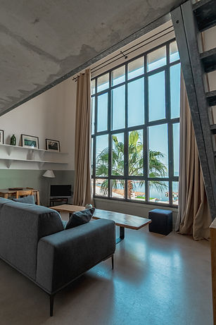 Loft contemporain, canapé gris, grande baie vitrée avec vue palmier