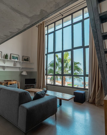 Grand salon moderne, baie vitrée, vue mer, palmier, appartement Corse.