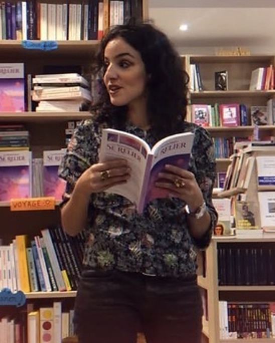 Anaïs Souada lisant un livre dans une librairie