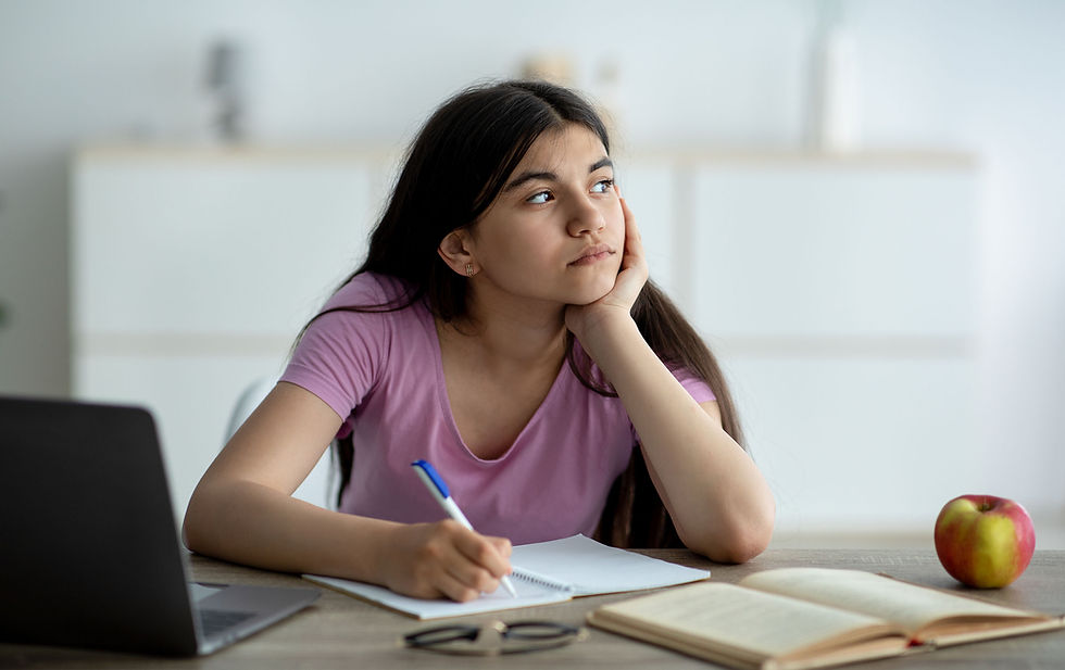 Distracted Indian teen girl studying, taking notes during lesson. Pensive adolescent participating in lecture, daydreaming with ADHD