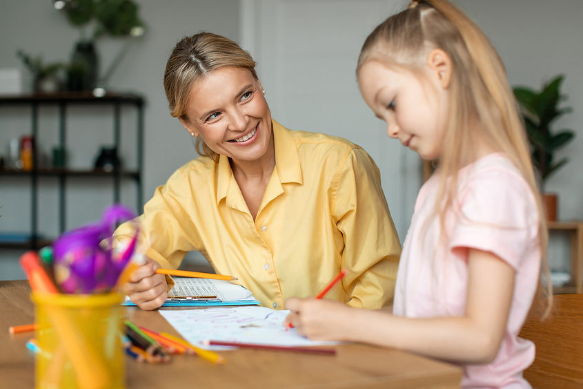 woman talking to a young girl as she completes some school work