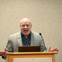 Man in sport jacket speaking from a podium.