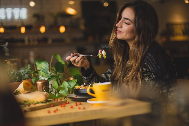 Jua herbs woman smiling in a lowlit restaurant eating healthy food