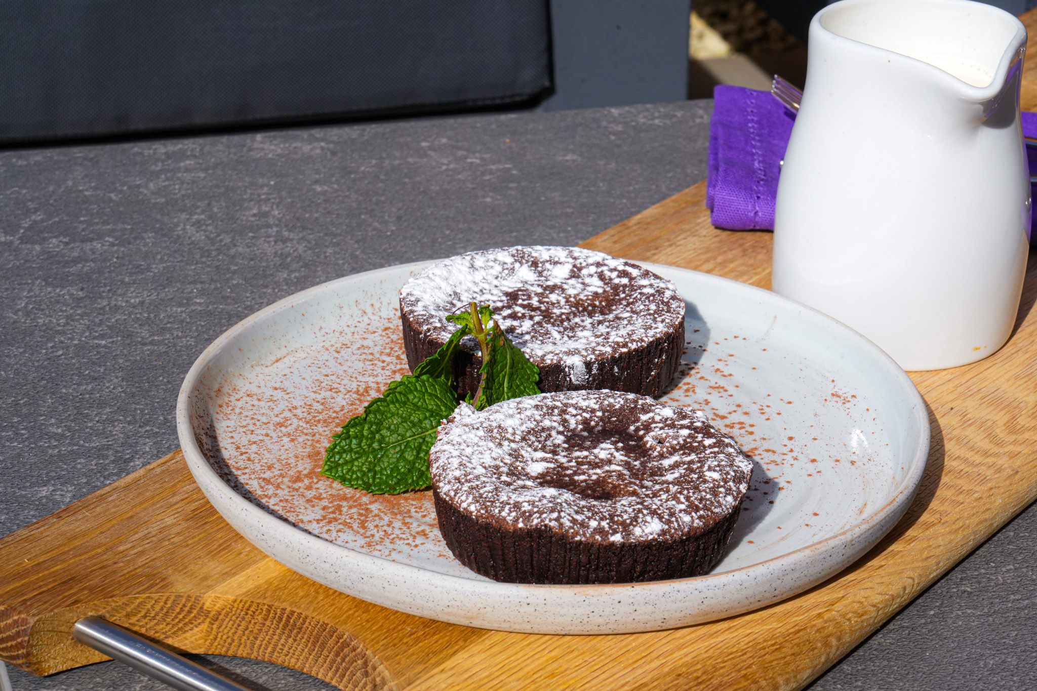 Chocolate fondants garnished with fresh mint on a grey plate