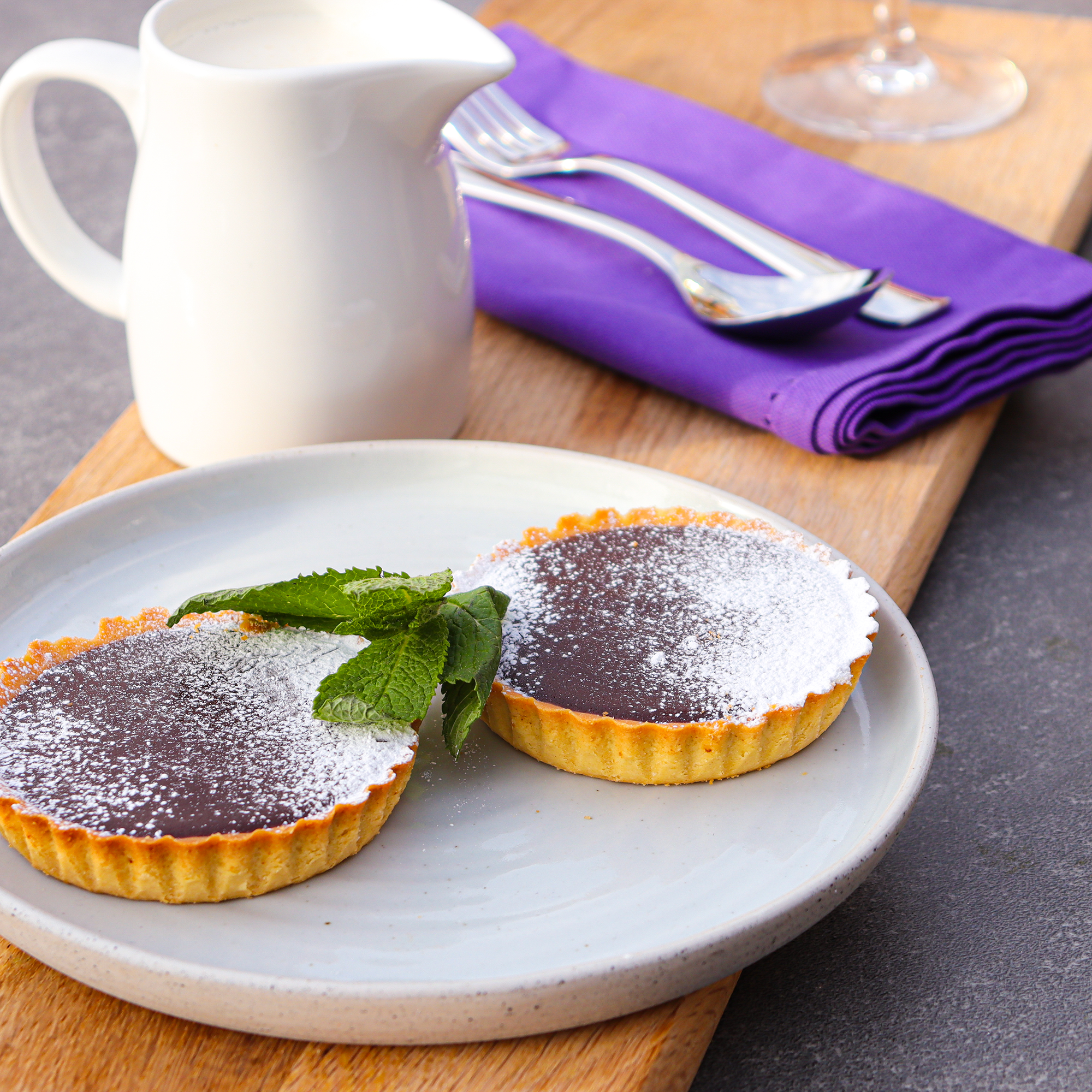 Close-up of chocolate and orange tarts dusted with cocoa and topped with mint