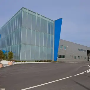 Modern industrial building with large glass panels and blue accents, representing Jurop’s advanced manufacturing facility.