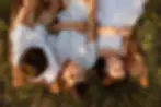 Three siblings lying on a blanket in long grass at golden hour — relaxed family photos in Sydney Nor