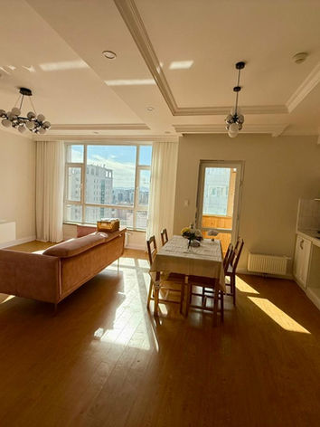 Modern, bright living room and kitchen in an apartment with large windows, Ulaanbaatar, Mongolia. Apartment for rent, city living.