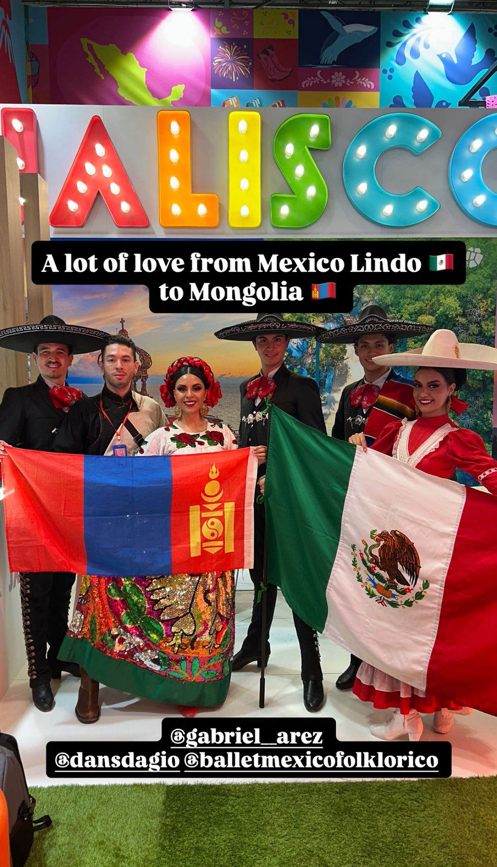 A group photo at the Jalisco pavilion featuring Anna Travel's representative with the Mongolian flag and Mexican performers in traditional Charro and Folklorico attire holding the Mexican flag.